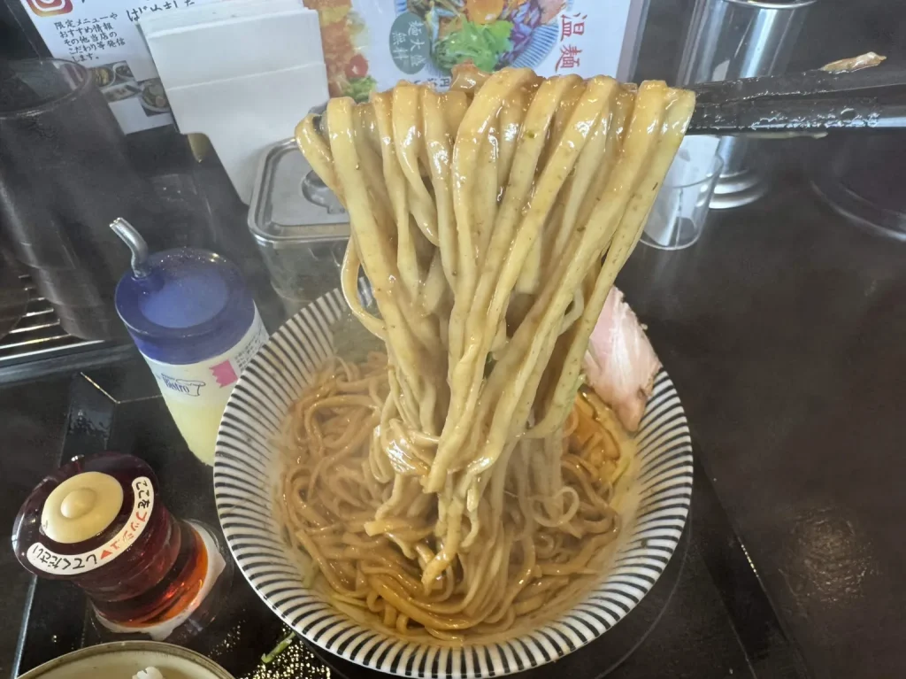 濃厚な魚介スープと魚粉が絡む平打ち太麺のリフト