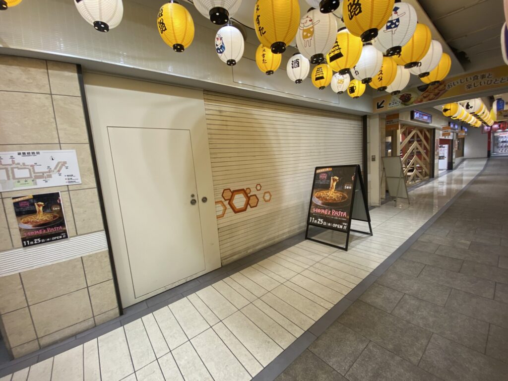 グランフェスタ5番街の出店予定区画。シャッターの前にホームズパスタの告知看板