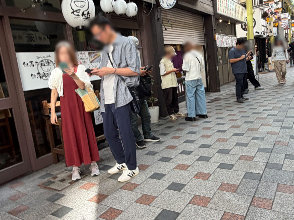歩道沿いでスマホを手にする人たち